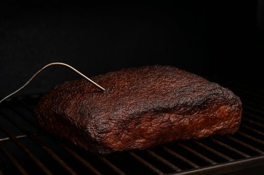 Plateauphase beim BBQ - Ein Stück Fleisch mit Kerntemperaturfühler auf einem Grillrost.
